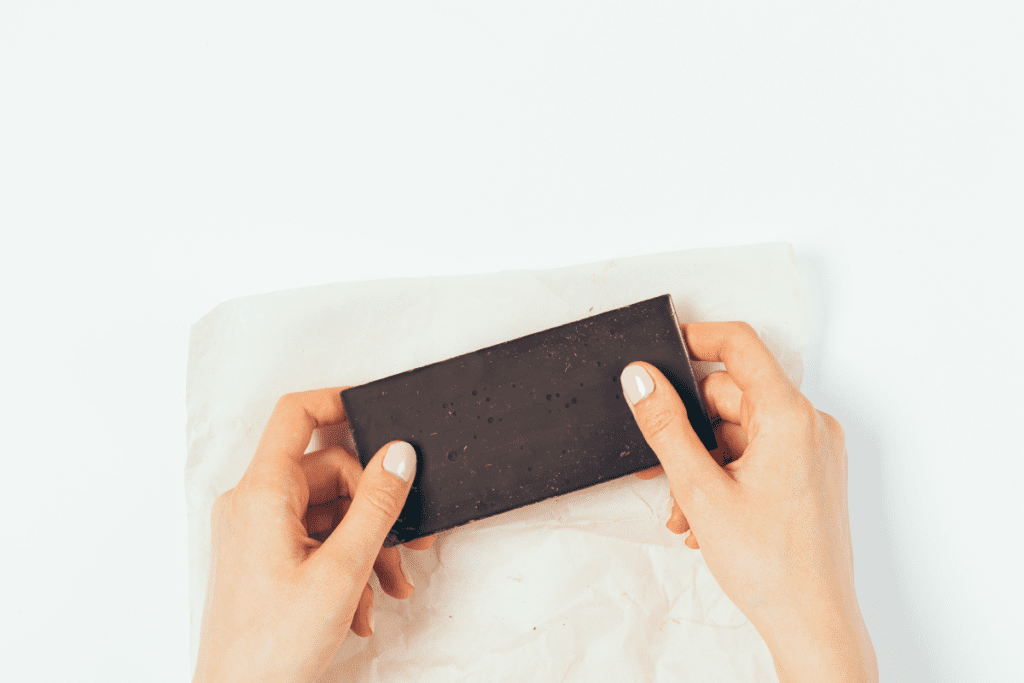 mãos femininas segurando uma barra de chocolate amargo